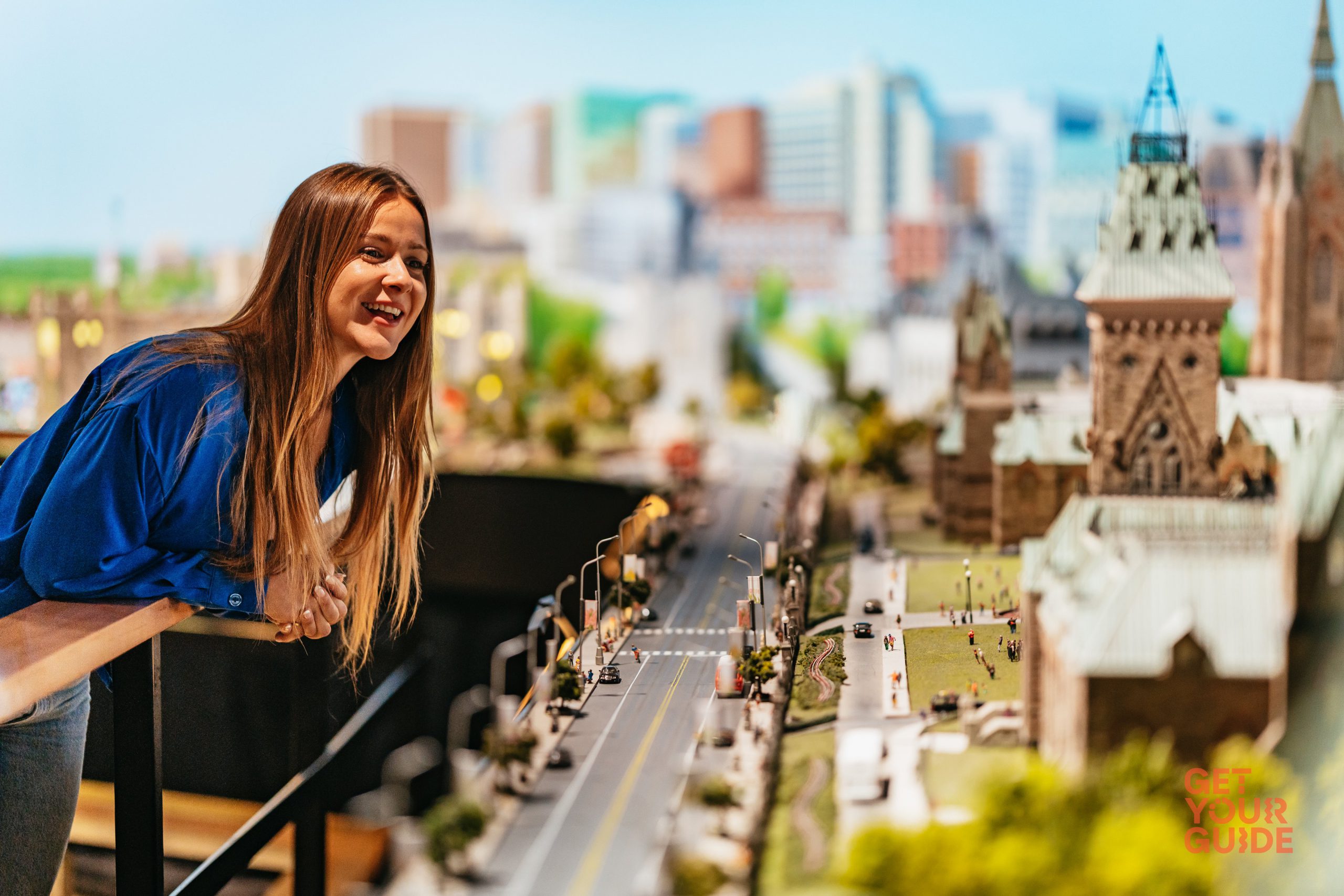 A women in a blue shirt is looking at a miniature version of the Parliament buildings in Ottawa, Ontario